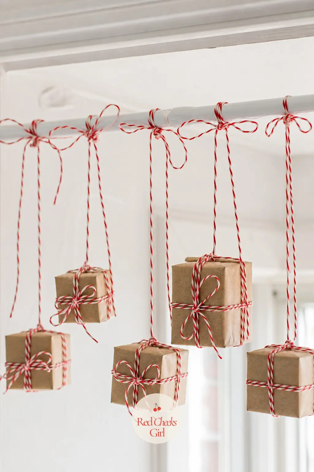 A Tension Rod Strung With Mini Wrapped Gift Box Ornaments — A tension rod needs no fixing to the wall and spans a window nook in seconds. Apartment christmas