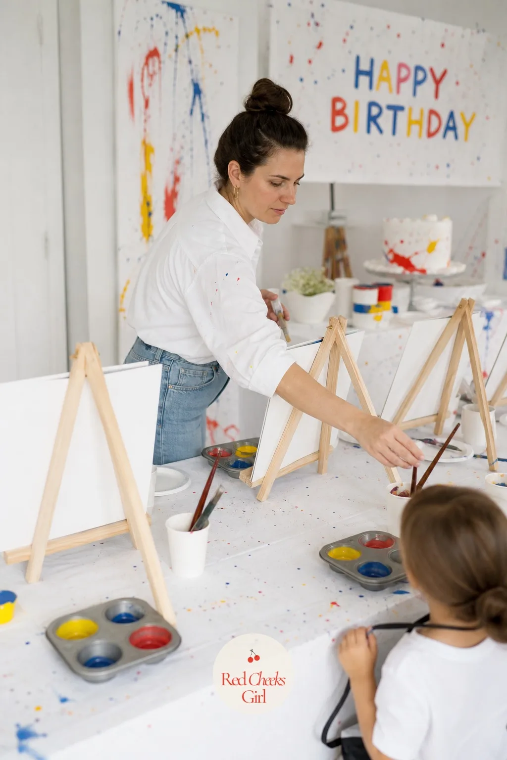 Mini Easel Paint Station For Every Child — Each seat gets its own small wooden easel with a precut art board clipped in place, a muffin tin holding three or