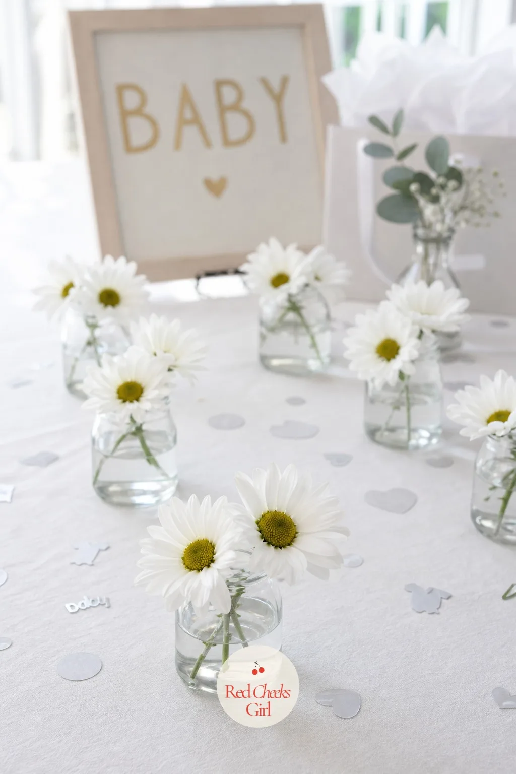 Baby Food Jars With Daisies — The same small jars, used instead as tiny vases, hold two or three white daisies with yellow centers each, scattered across the
