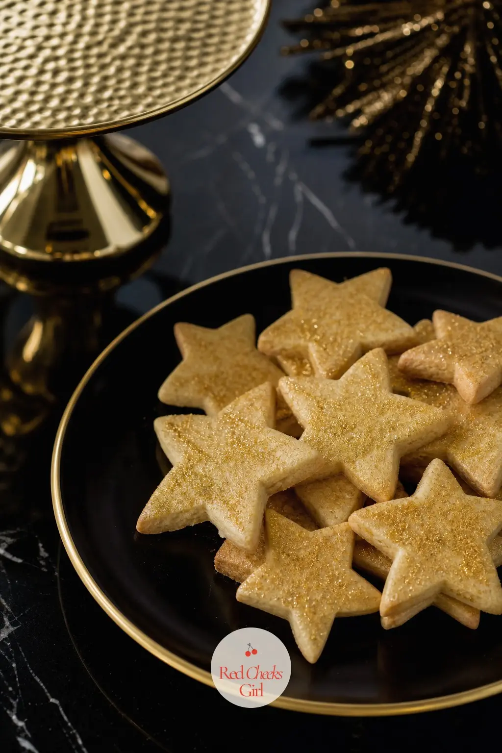The Cookie Plate, Set Out for a Midnight Snack — A black plate edged in gold holds a small stack of star-shaped shortbread dusted with edible gold, set out for