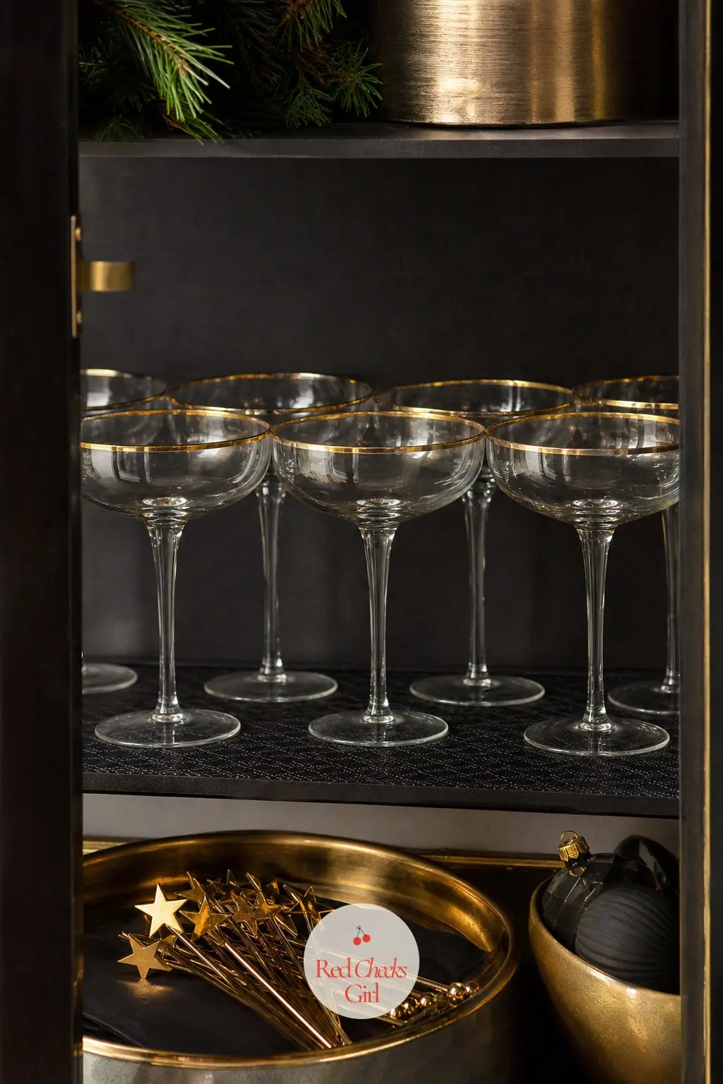 The Drinks Cabinet, Stocked with Gold-Rimmed Coupes — Open shelves hold a neat row of coupes and a small brass tray of stirrers, each one topped with a tiny