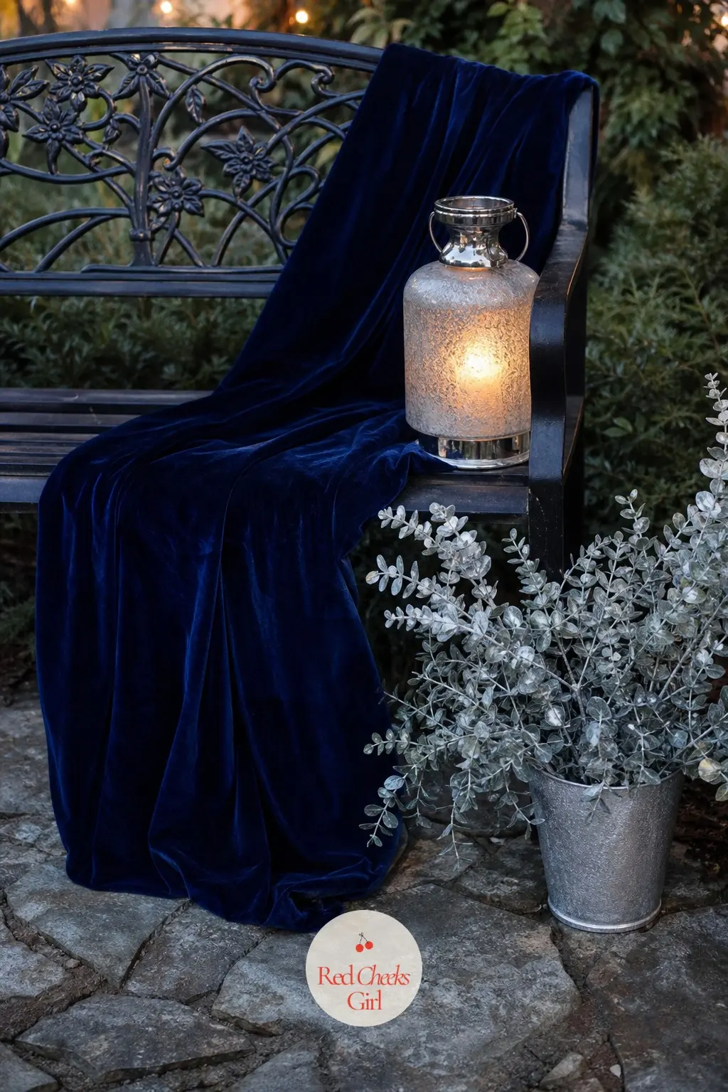 The Garden Bench, Draped in a Velvet Throw and Silver Lantern — A bench along the path carries a navy velvet throw folded in half and a single frosted glass