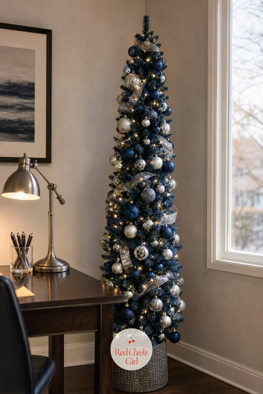 A Narrow Navy Tree Behind the Desk — A slim artificial tree tucked into the corner behind a home office desk, navy deep enough to read as serious rather than