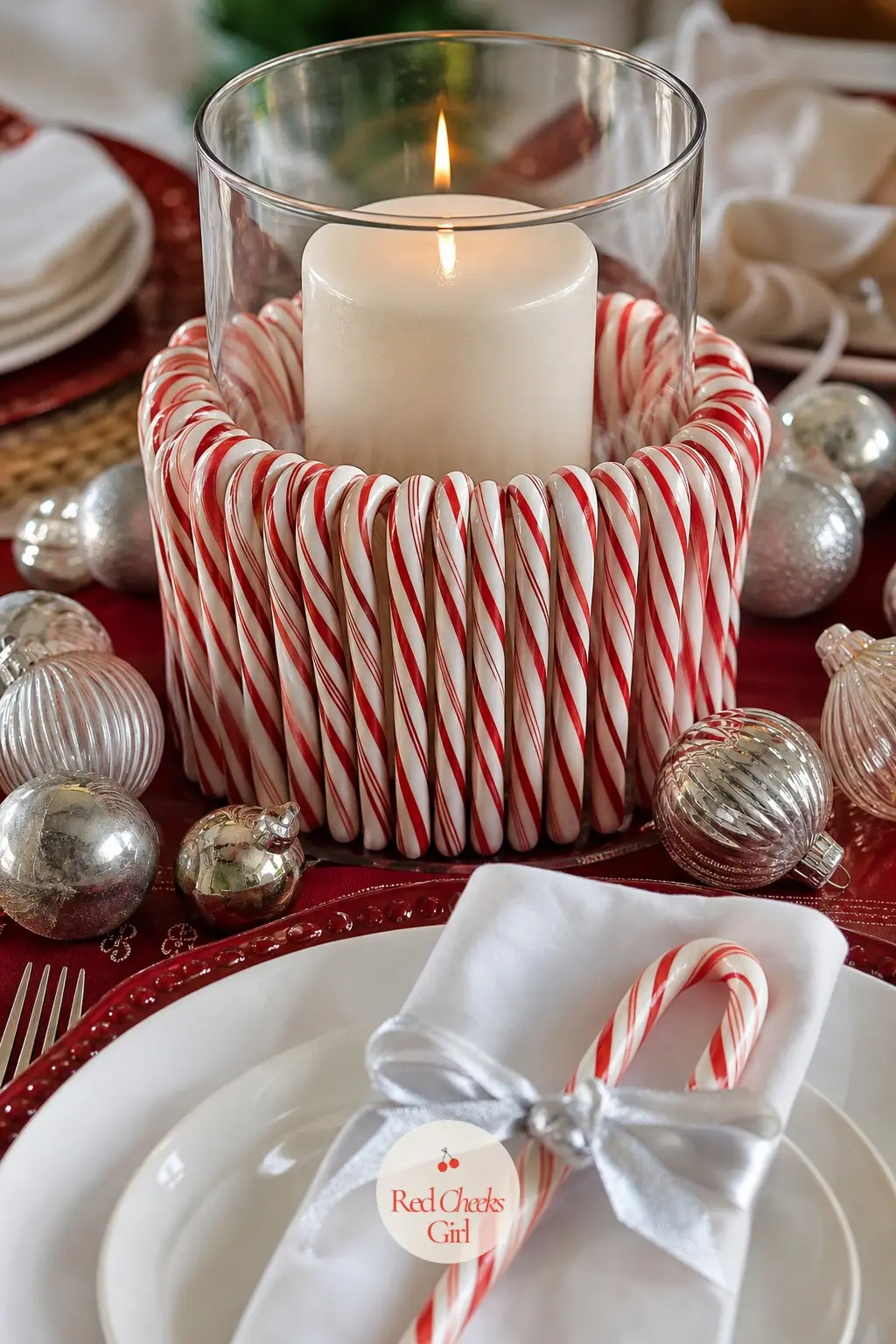 A Centrepiece Built From Striped Candy — A wide glass hurricane holds a tall white candle, packed around its base with real candy canes standing upright