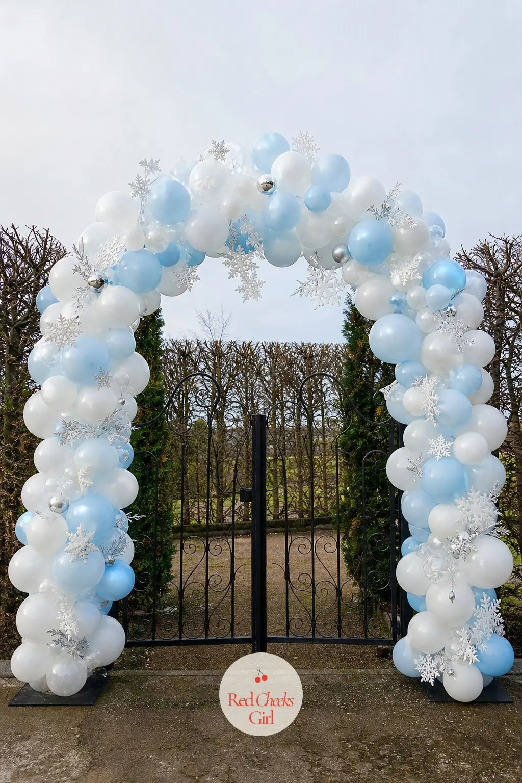 A Snow White and Ice Blue Balloon Arch Curved Over the Garden Gate — White and ice blue together reads as snow rather than winter wedding, which is the