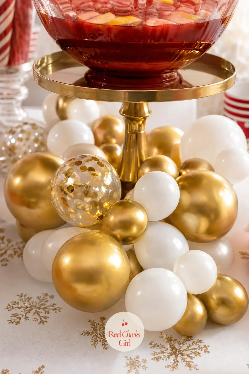 A Cluster of Gold Orb Balloons Spilling From the Punch Bowl Stand — A tiered stand that usually holds a punch bowl gets a skirt of gold and white round