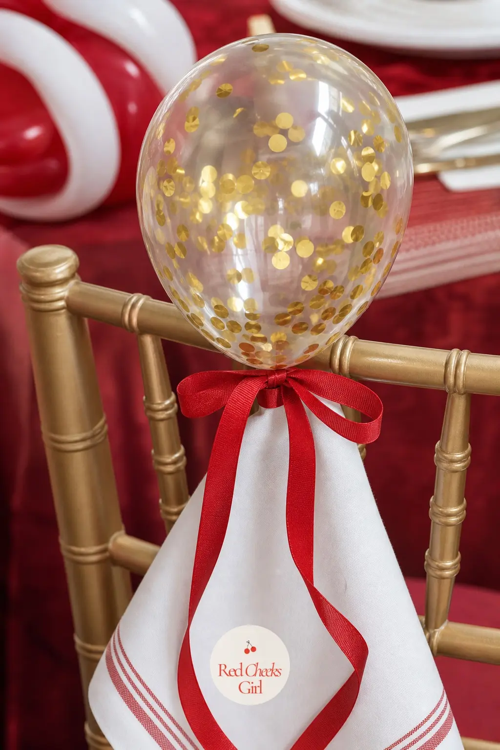 A Confetti Balloon Napkin Weight Tied to Every Chair — A single small gold confetti balloon tied with red ribbon to each chair back doubles as a seat marker
