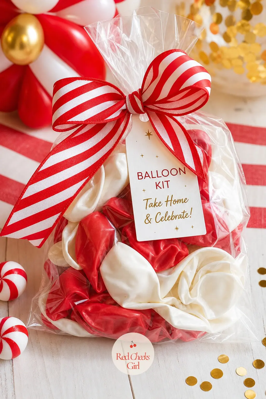A Take-Home Balloon Kit Wrapped in Candy Cane Ribbon — A flat cellophane bag holding a handful of uninflated red and white balloons, a straw and a length of