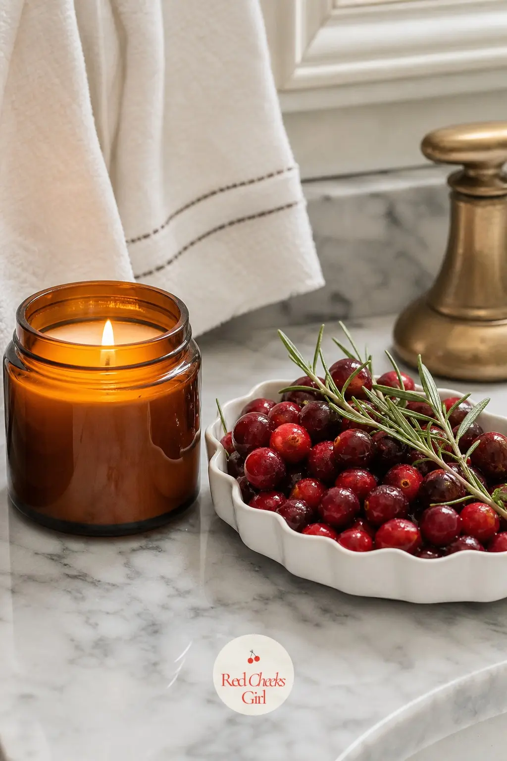 A Squat Amber Glass Candle Set Beside a Shallow Dish of Fresh Cranberries and Rosemary — An amber glass candle in a low jar, set right next to a shallow dish