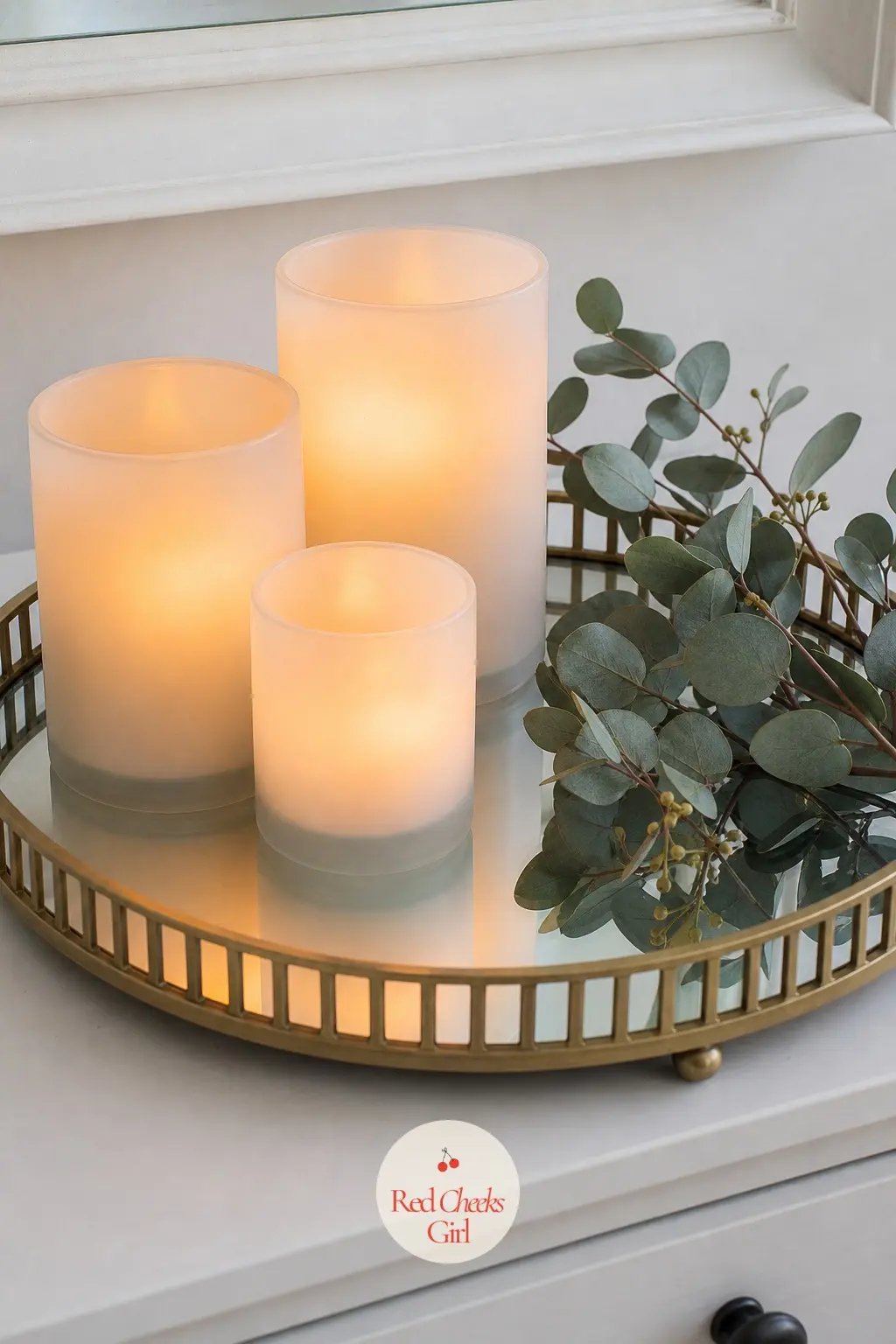 A Mirrored Tray Holding Flameless Candles and a Sprig of Eucalyptus — A mirrored tray doubles any light set on it, which matters on a dresser that otherwise