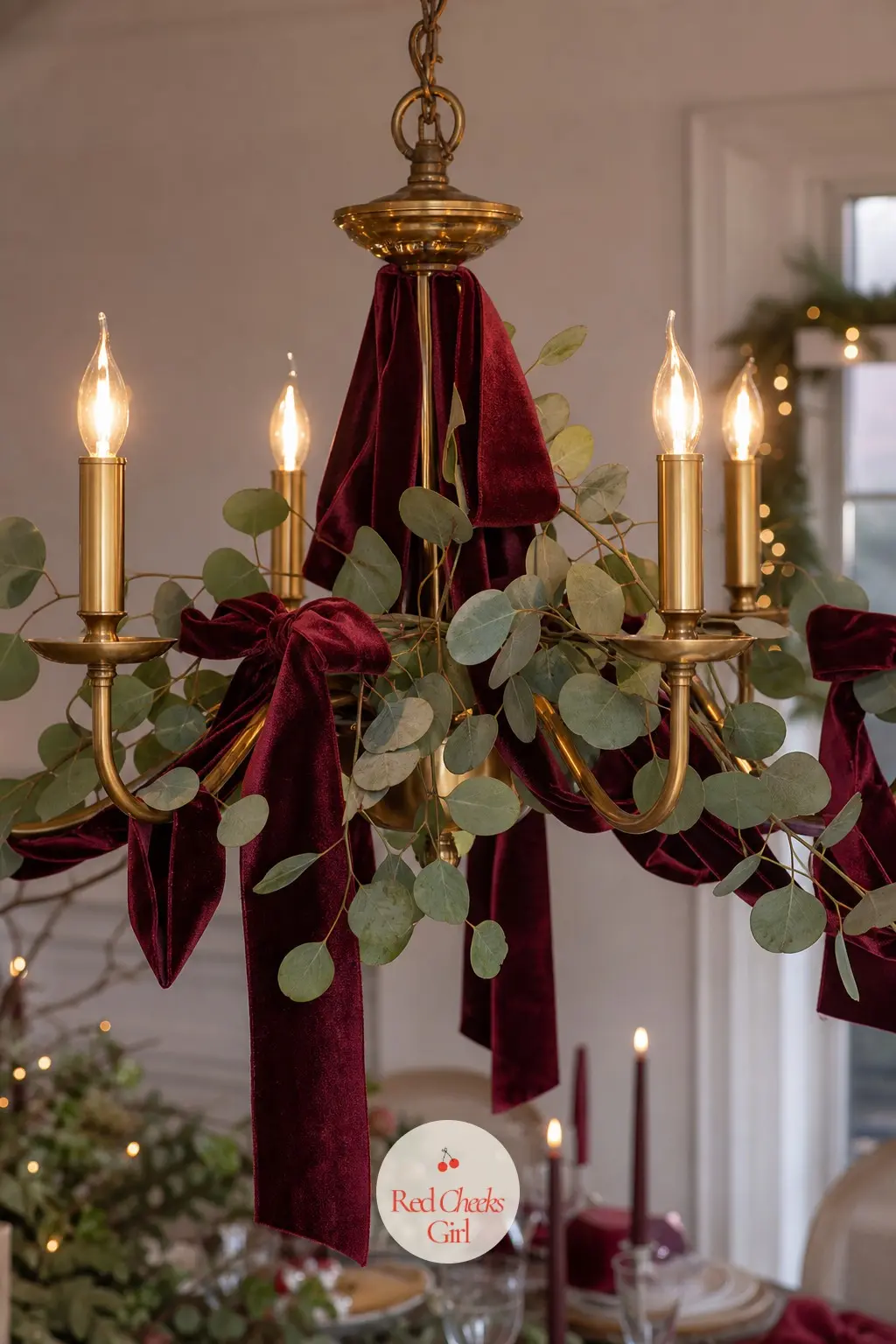 Burgundy Velvet and Eucalyptus Brass Chandelier — A brass dining room chandelier wants weight it can actually carry, so loop faux eucalyptus through the arms