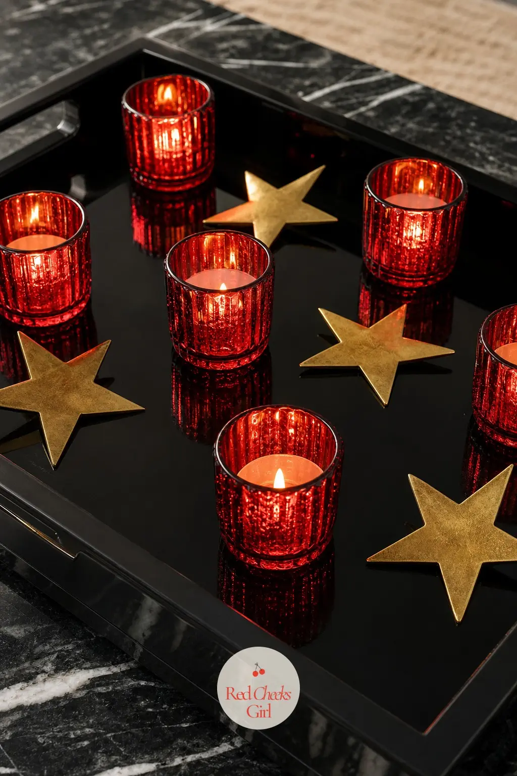 A Black Lacquer Tray Lined With Cranberry Votives and Brass Stars — A glossy black lacquer tray holds a row of ruby glass votives in deep cranberry, each one