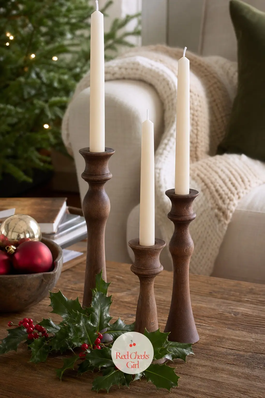 A Graduated Trio of Ivory Tapers in Turned Wood Candlesticks — Three ivory taper candles sit in turned wooden candlesticks of different heights, with a sprig