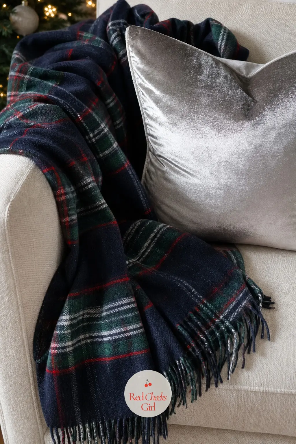 A Navy Tartan Throw with a Silver Velvet Pillow — Navy tartan reads less expected than red and sits comfortably in a grey or navy room where red would clash
