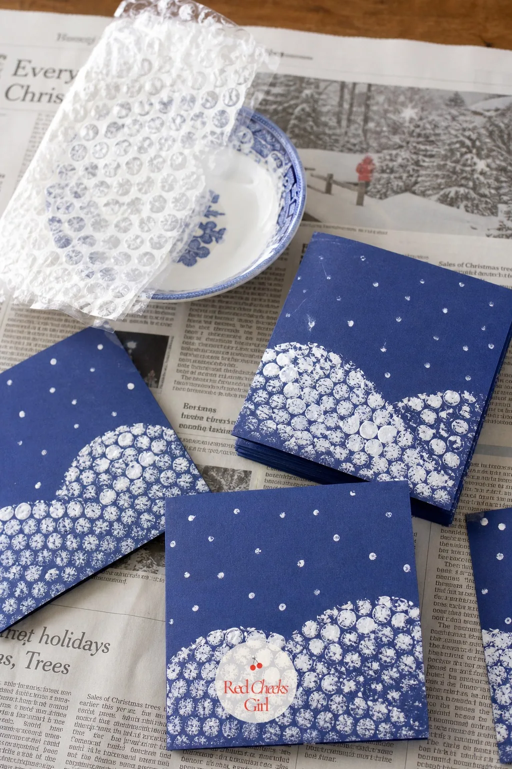 Bubble Wrap Snow Print Cards — A sheet of bubble wrap dipped in white paint and pressed onto deep blue cardstock leaves a texture that reads as drifted snow