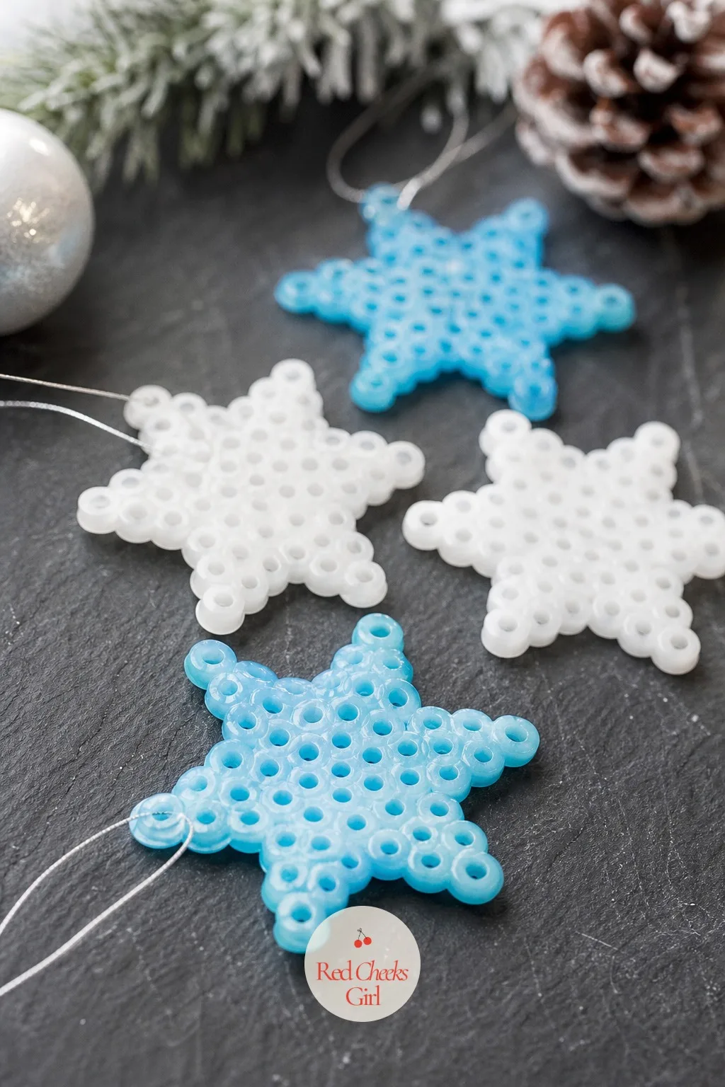 Melted Pony Bead Snowflakes — White and icy blue pony beads arranged in a snowflake pattern on a baking tray go into a low oven for a few minutes and come out