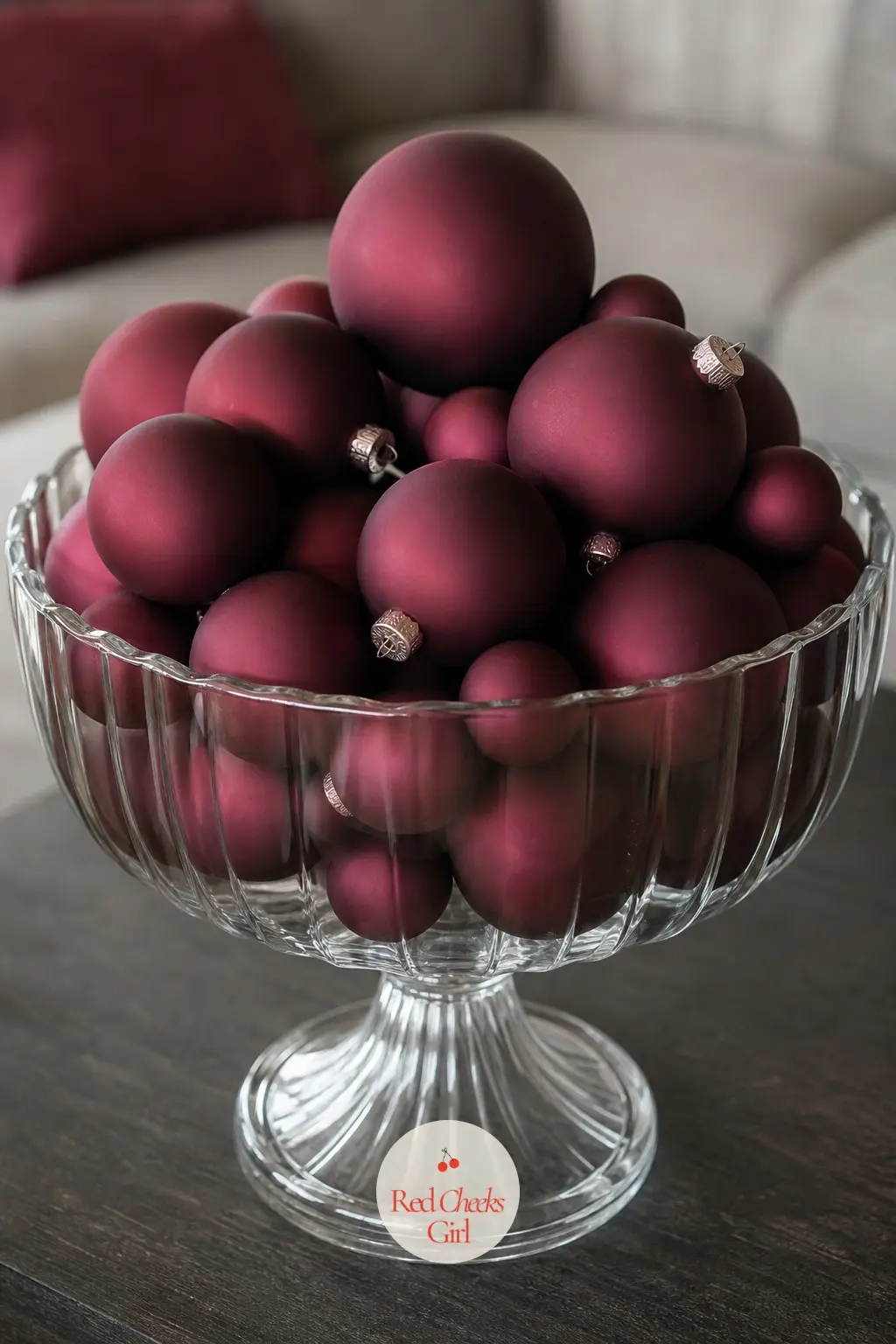 A Bowl of Ornaments in One Colour as a Centerpiece — One large glass pedestal bowl, filled entirely with matte ornaments in a single colour such as deep