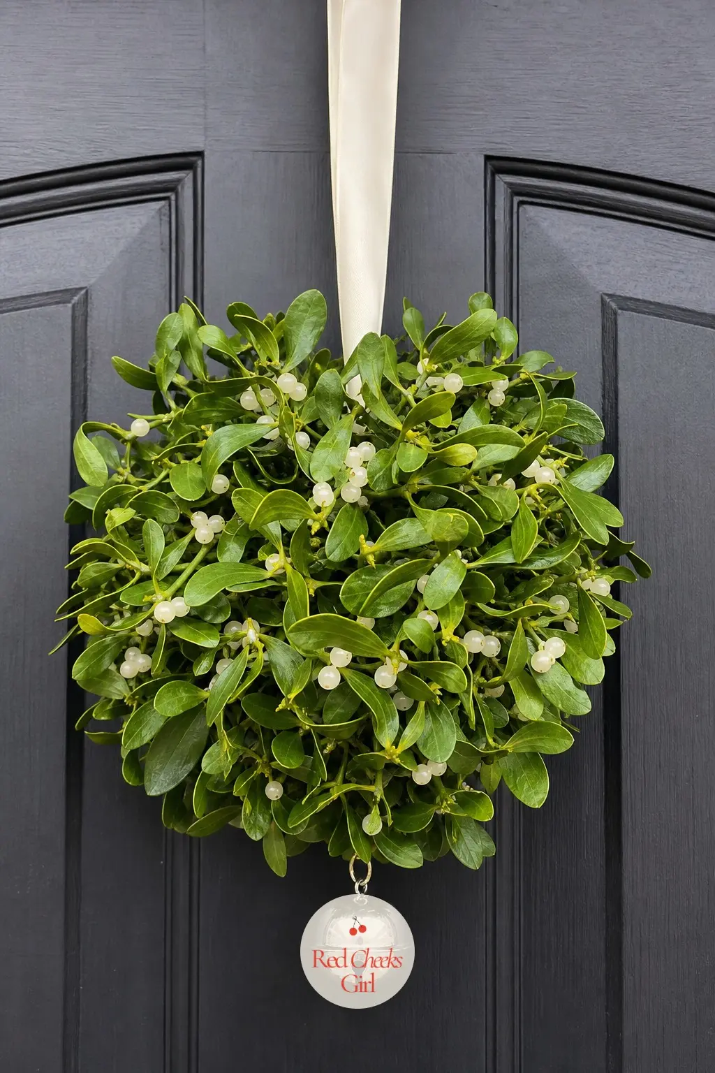 A Kissing Ball Hung Dead Center at Eye Level — Skip the wreath shape entirely and hang a round mistletoe ball instead, ivory satin ribbon looping it to the