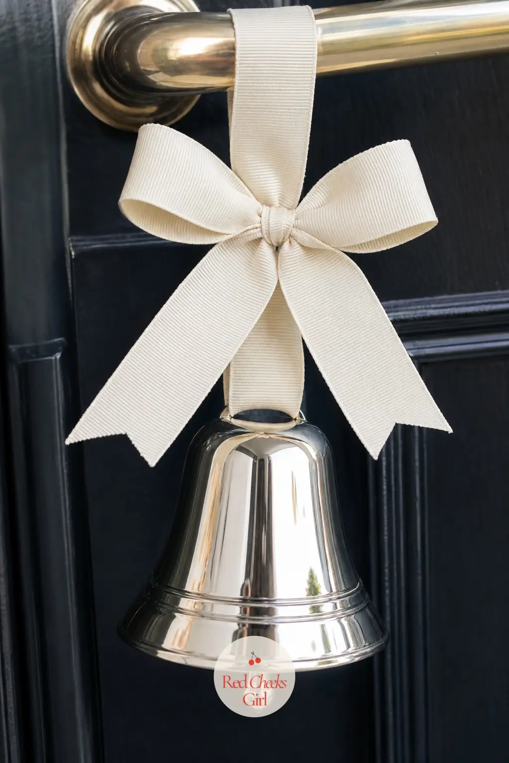 A Single Polished Silver Bell on Ivory Grosgrain Ribbon — One polished silver bell, not a cluster, hangs from a length of ivory grosgrain ribbon tied to the