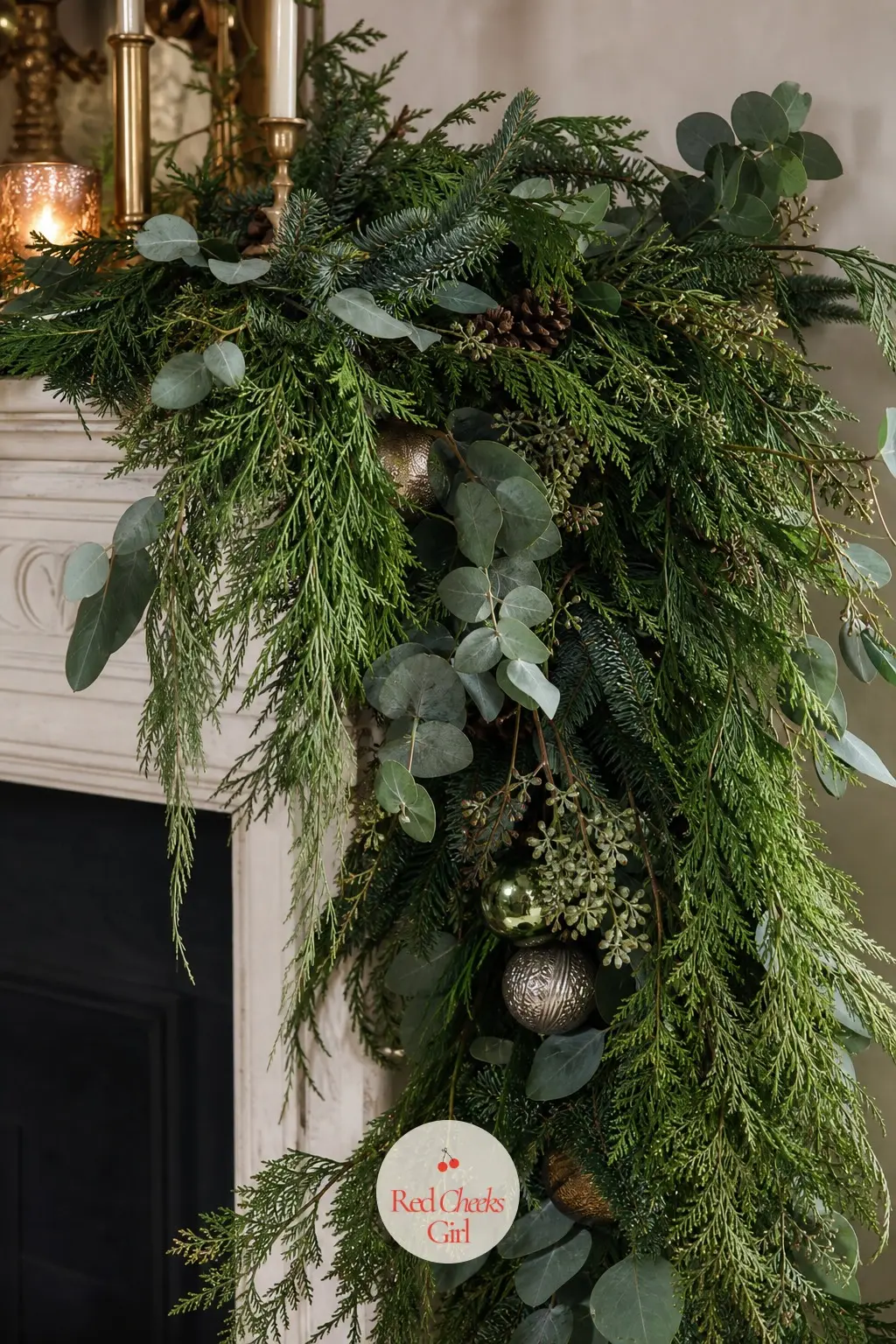 Asymmetric Mixed Greenery Spilling Off One End — A mantel dressed heavy on one side, piled thick with layered deep green and dusty blue greenery, then left to
