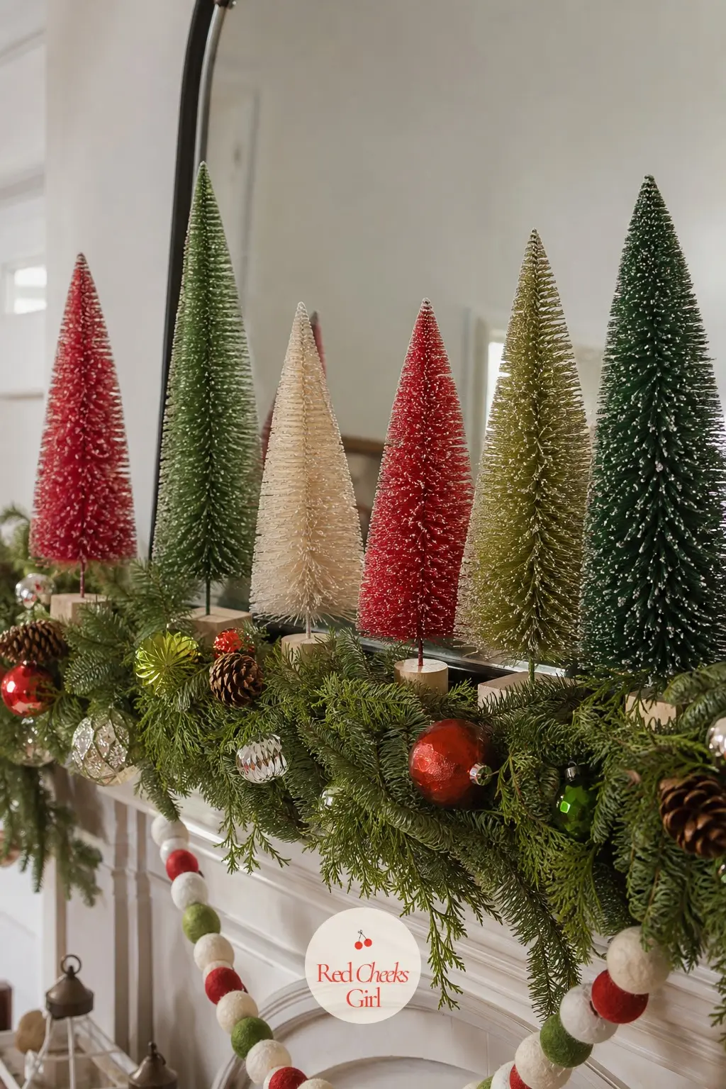 Bottle Brush Trees Lined Along A Mantel Garland — A row of small red, green and white bottle brush trees standing upright along a plain mantel garland brings a