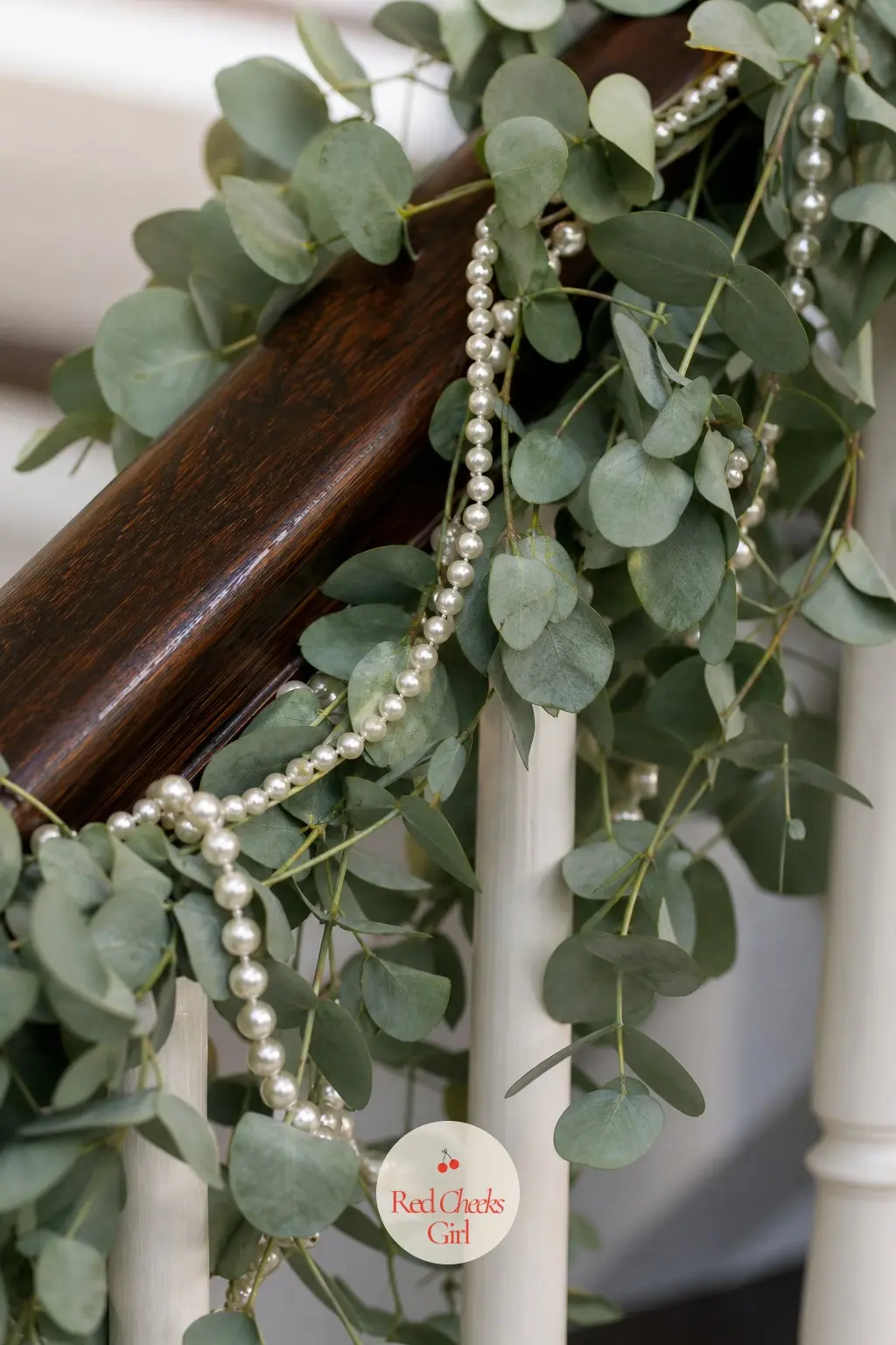 Eucalyptus And Pearl Strands — Silvery eucalyptus along a staircase banister, threaded through with strands of cream pearls, is the quietest version of elegant