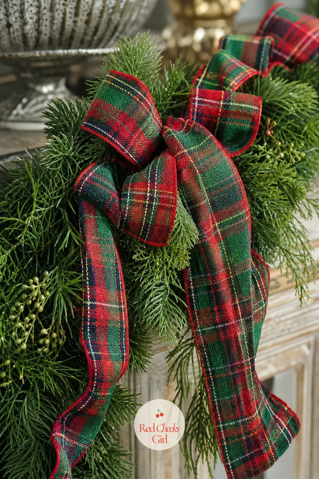 Greenery Wrapped In Plaid Ribbon — Classic red, green and cream tartan ribbon wound around a plain faux pine garland along an entry console turns a basic