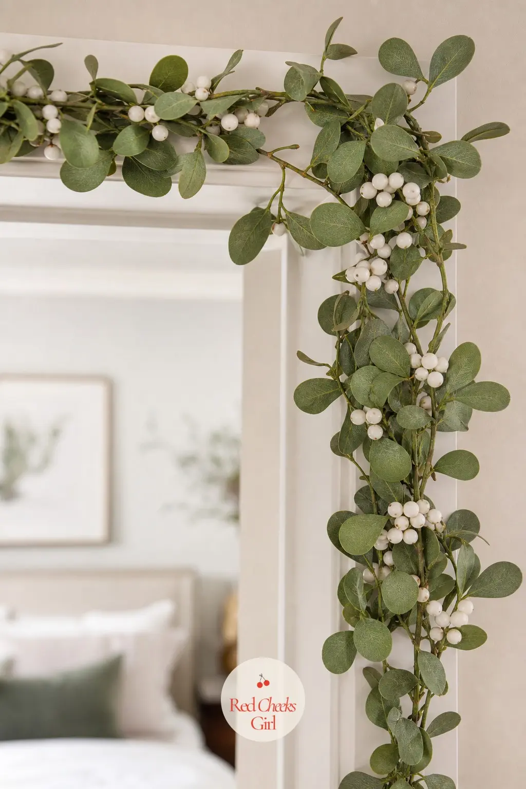 Mistletoe And White Berry Garland — A soft sage mistletoe garland studded with clusters of white berries around a bedroom doorway keeps the tradition without