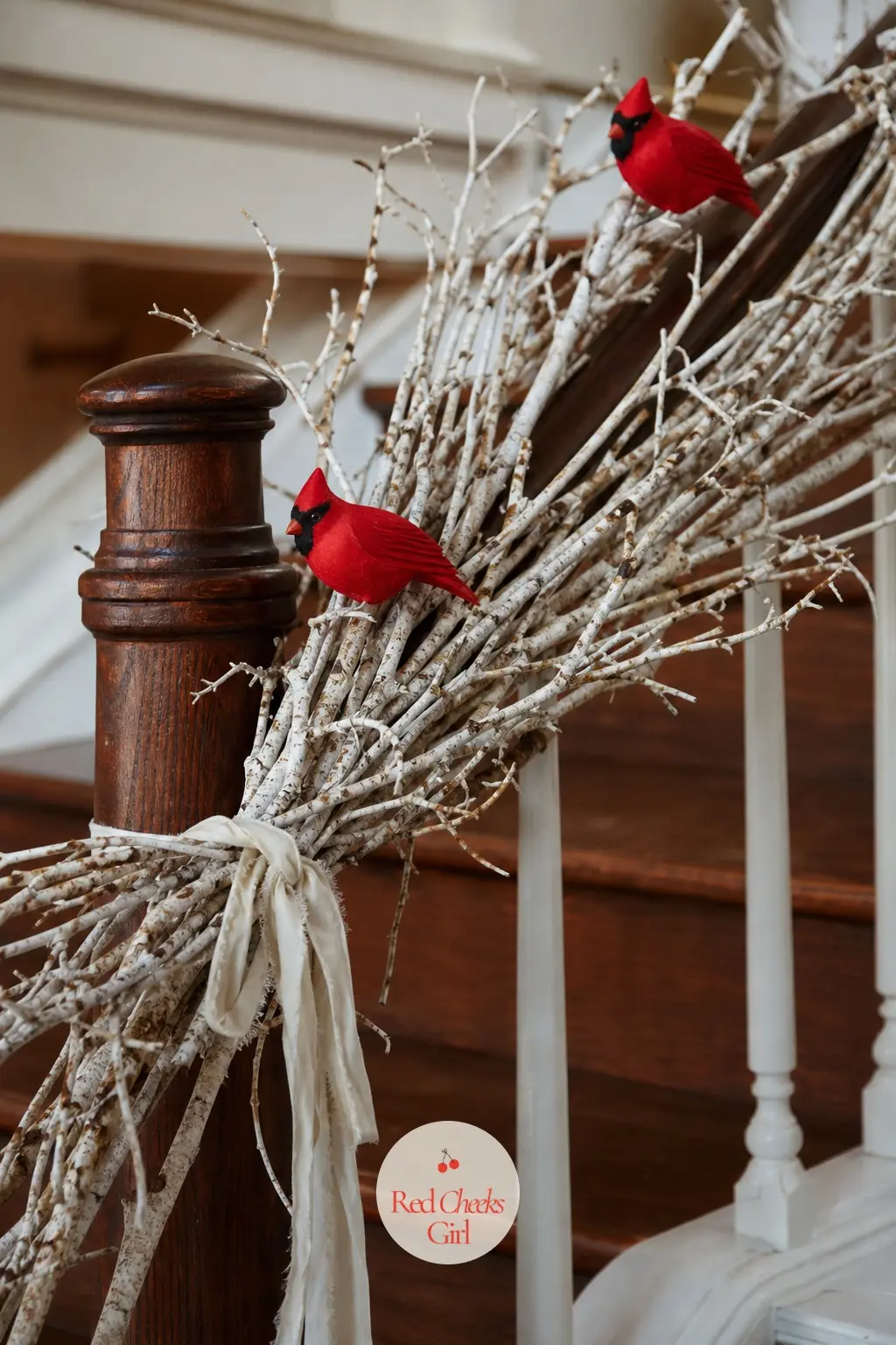 Birch Branch Garland with Cardinal Accents — Bare white birch branches, tied in loose bundles rather than a continuous strand, give the staircase a woodsy