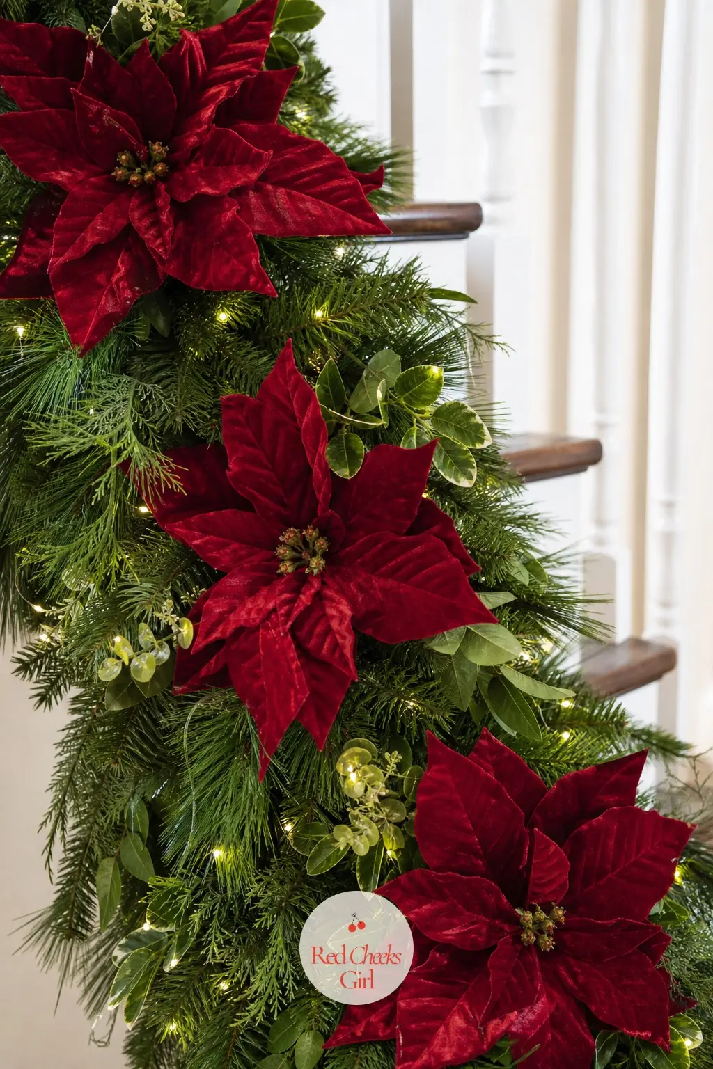 Velvet Poinsettia Blooms Tucked Along the Garland — A full fir garland gets an instant lift when deep crimson velvet poinsettia blooms sit tucked in at even