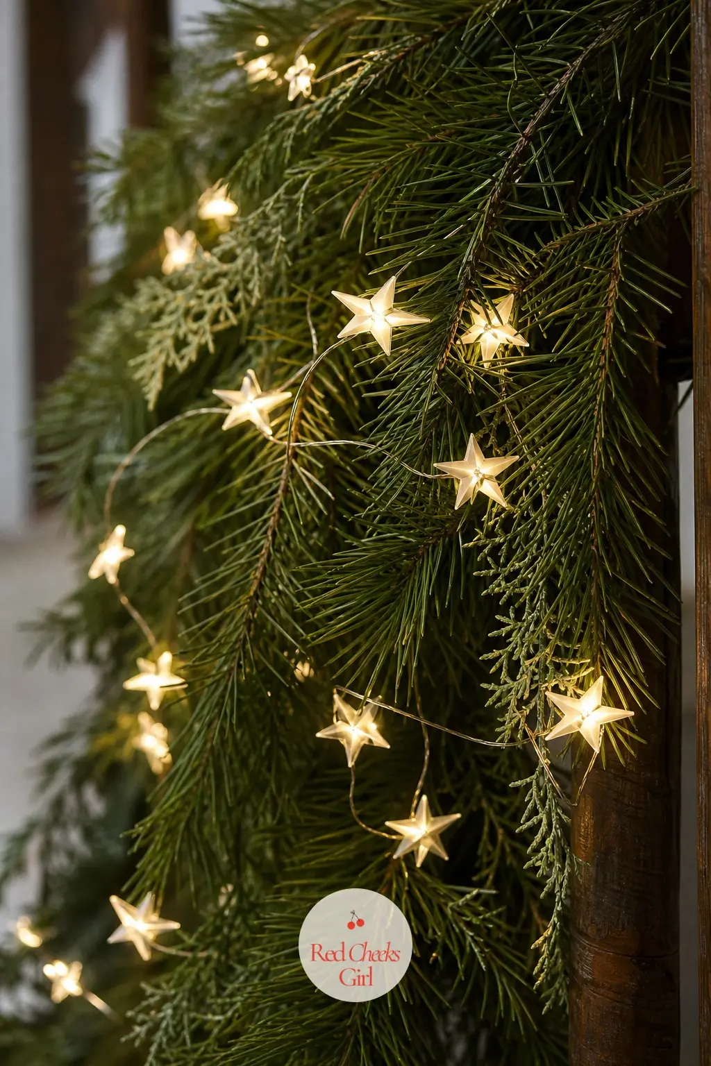 Star String Lights Woven Through Pine — Small gold star shaped string lights woven through a pine garland along the staircase is a quieter, more specific