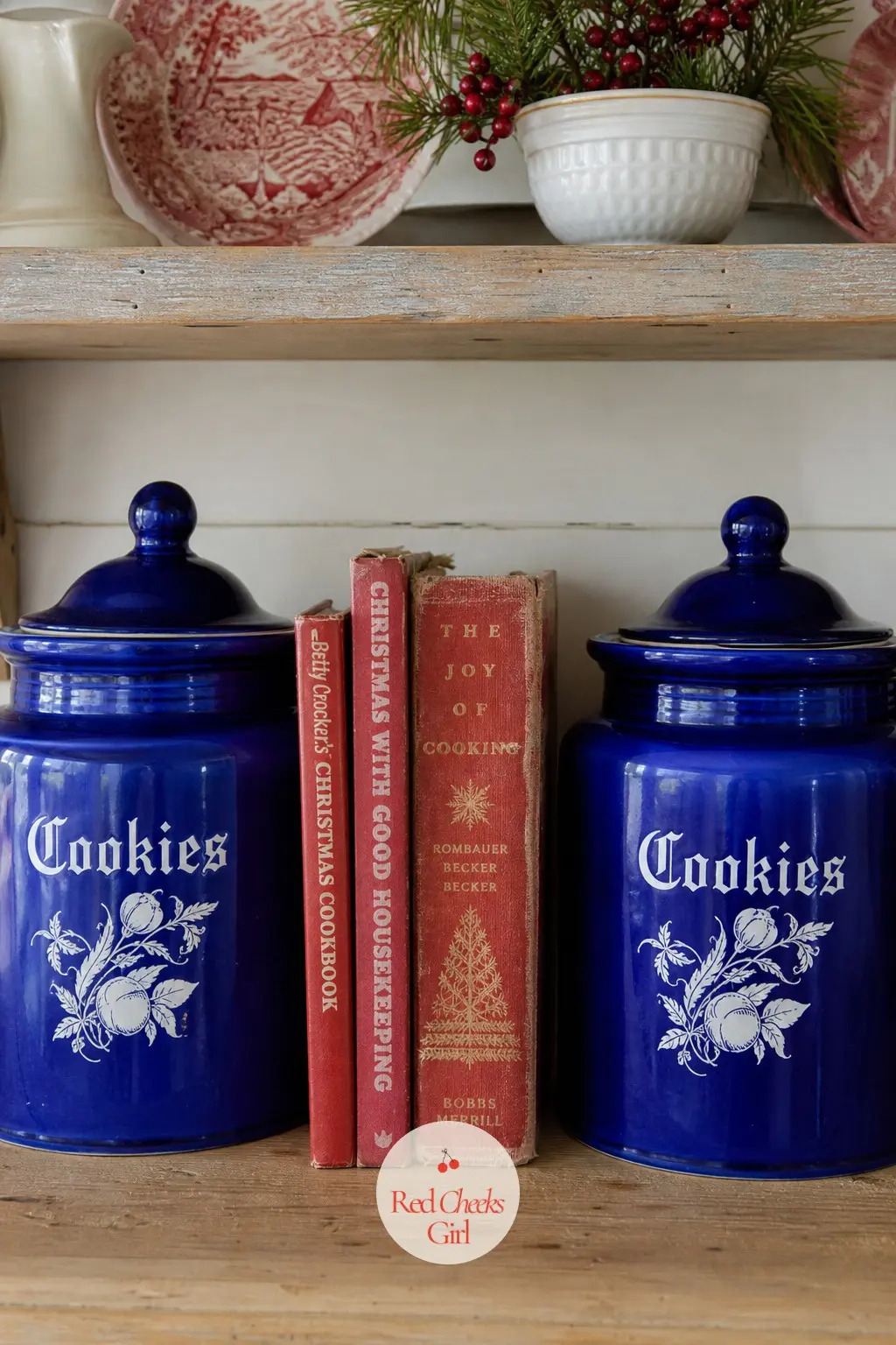 A Pair of Cobalt Cookie Jars Flanking a Stack of Vintage Christmas Cookbooks — Two matching cobalt cookie jars set on either side of a short stack of worn