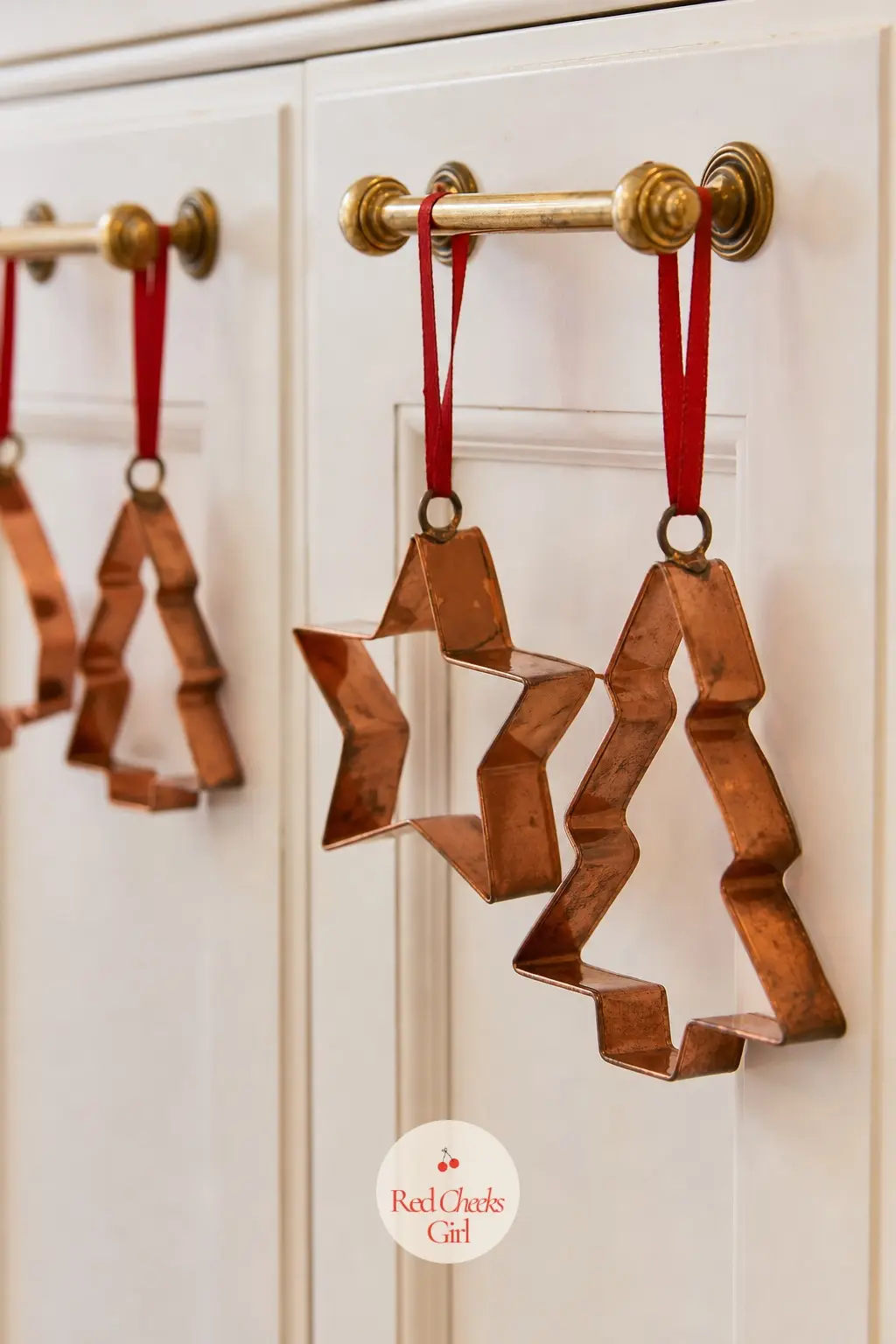 A Row of Vintage Copper Cookie Cutters Clipped to Cabinet Pulls Like Ornaments — Old copper cookie cutters already look like ornaments, so clipping a few to
