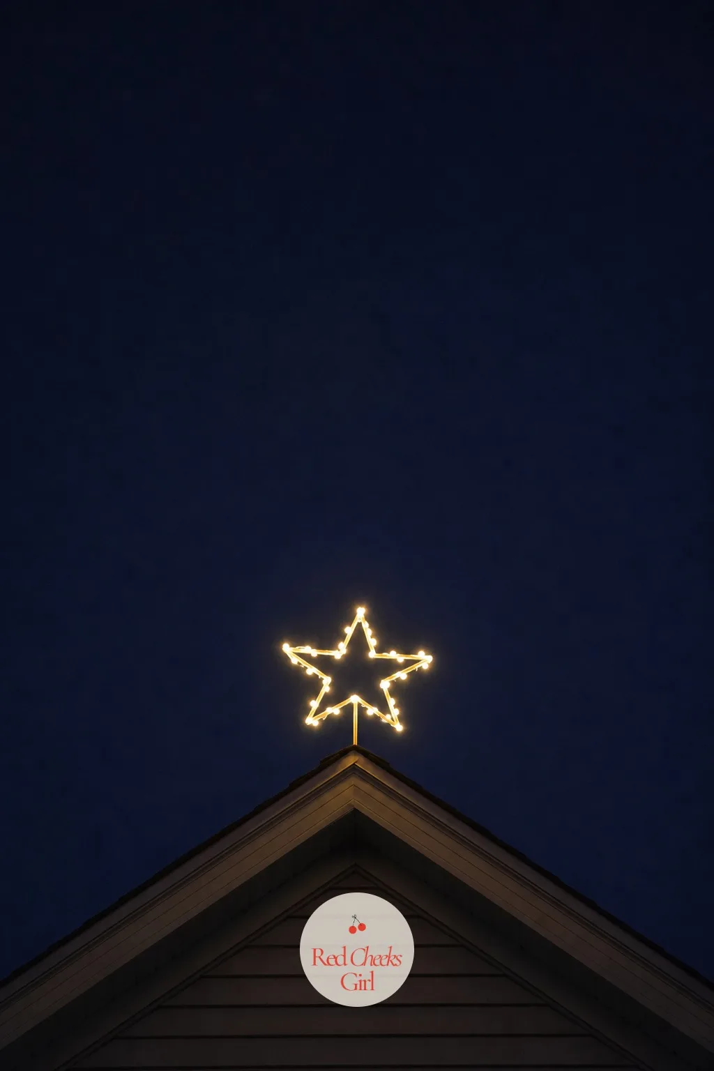 A Single Lighted Star at the Roof Peak — One clean symbol at the very top of the house does more than a dozen scattered extras, because the eye has a single