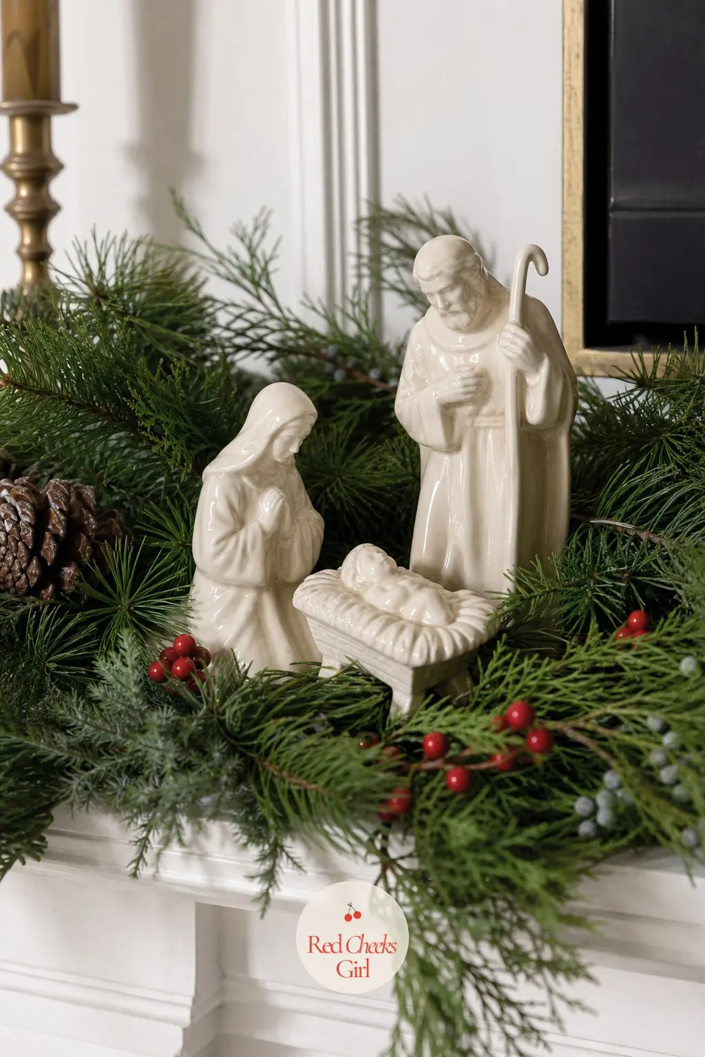 A Small Nativity Scene Tucked Into a Bed of Greenery — A simple wood or cream ceramic nativity set, nestled directly into the garland rather than displayed on