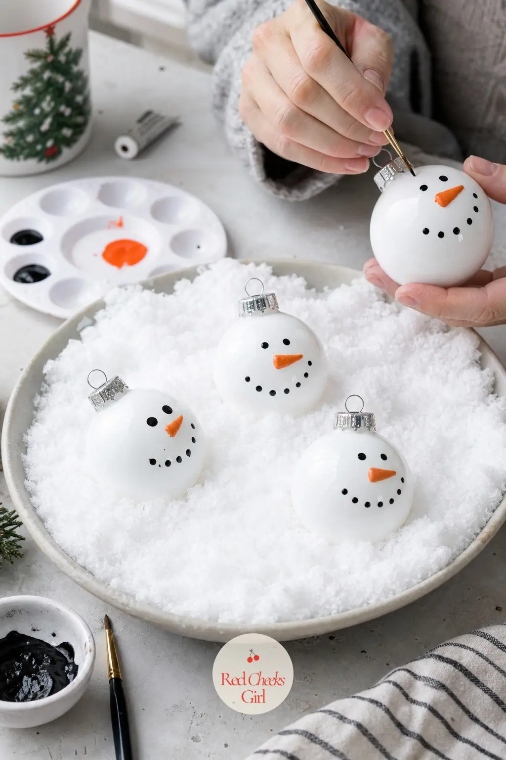 Snowman Family Tableau Ball — Three stacked white circles, a carrot-orange triangle, and two coal-black dots: easier to paint than it sounds, and the kind of