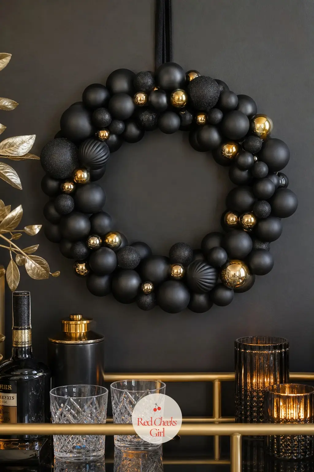 The Matte Black and Gold Monochrome Wreath for the Home Bar — Matte black ornaments against a scatter of gold balls make a wreath that reads as grown-up rather