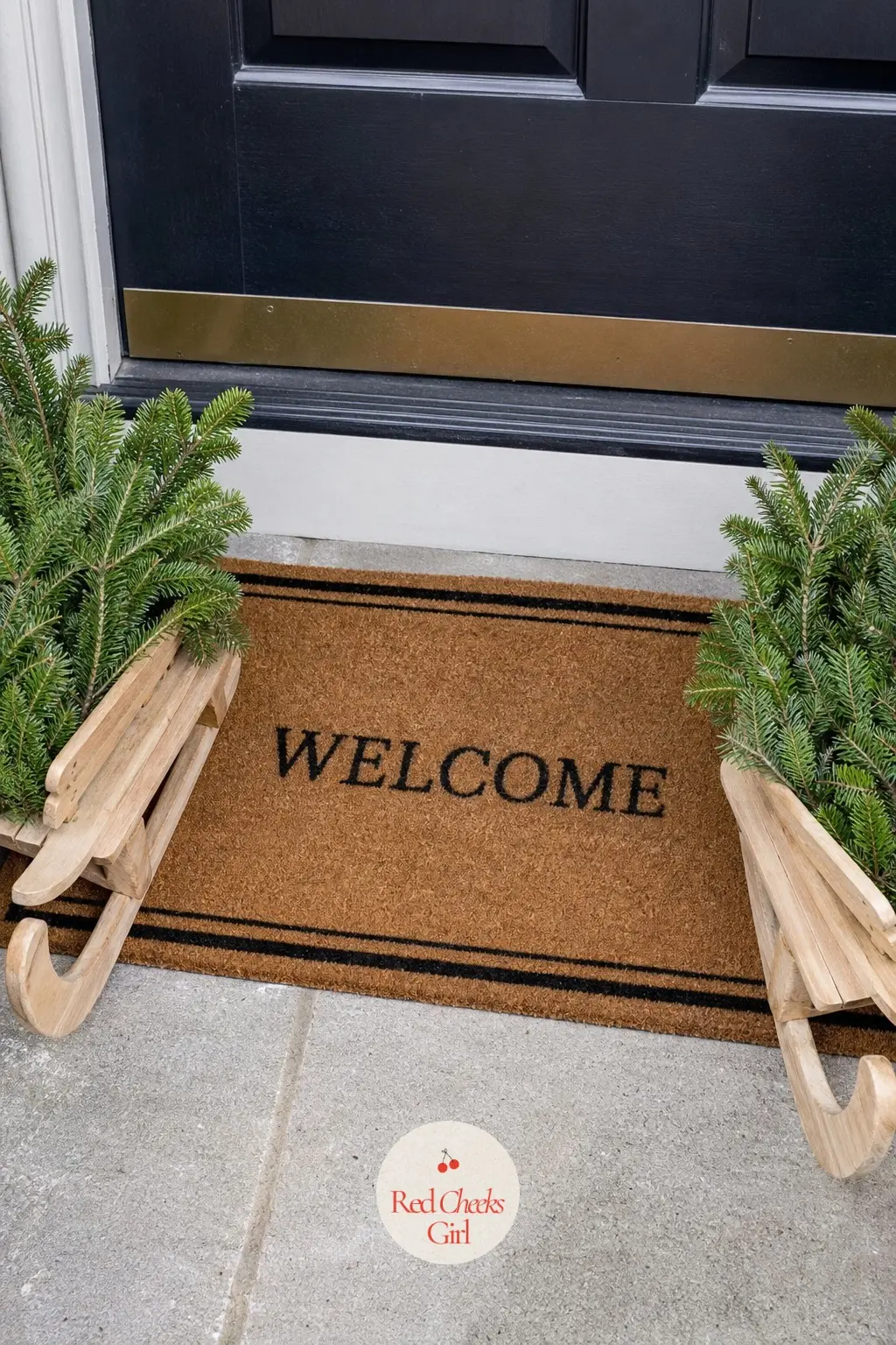 A Pair of Mini Sleds Flanking the Welcome Mat — Two small natural-wood sleds, one on each side of the mat, filled with fresh noble fir sprigs, give a porch