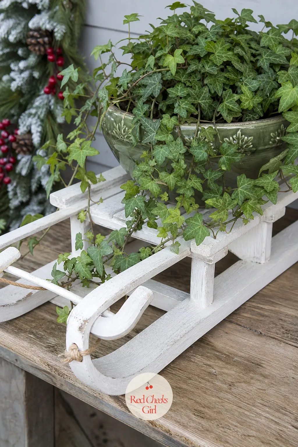 A Sled Repurposed as a Plant Stand for Trailing Ivy — Lay a white-painted sled flat on a porch bench and set a green ceramic pot of trailing ivy on top