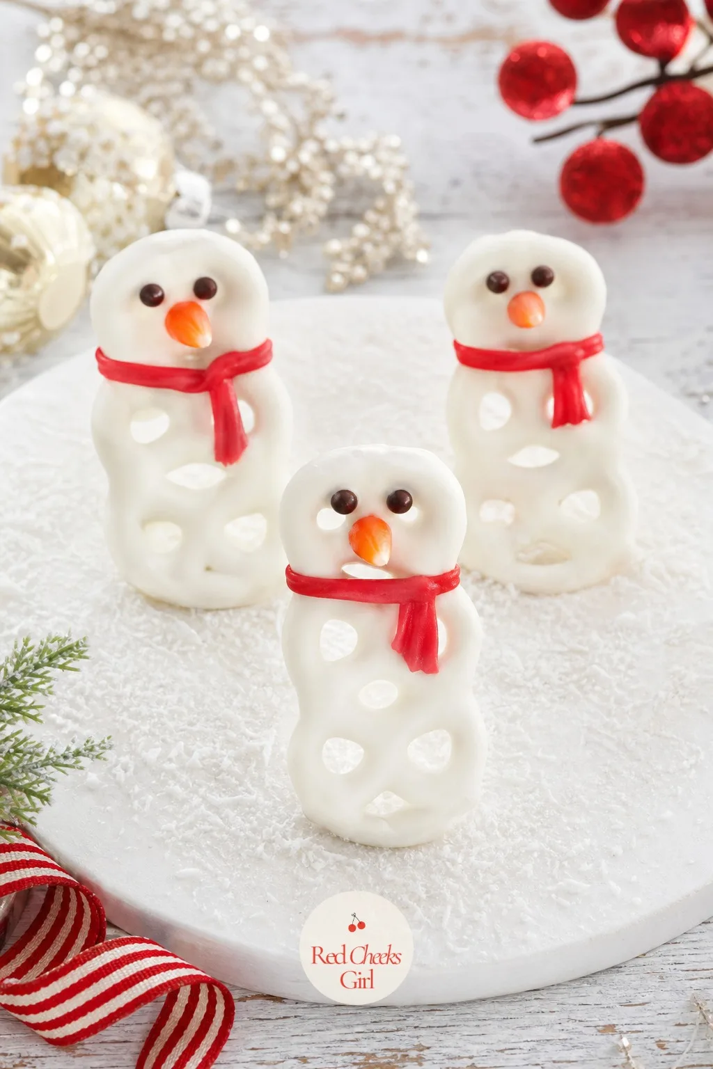 Pretzel Snowmen — Three pretzel rings stacked and dipped look nothing like a snowman until the orange candy corn nose goes on, and then suddenly they do.