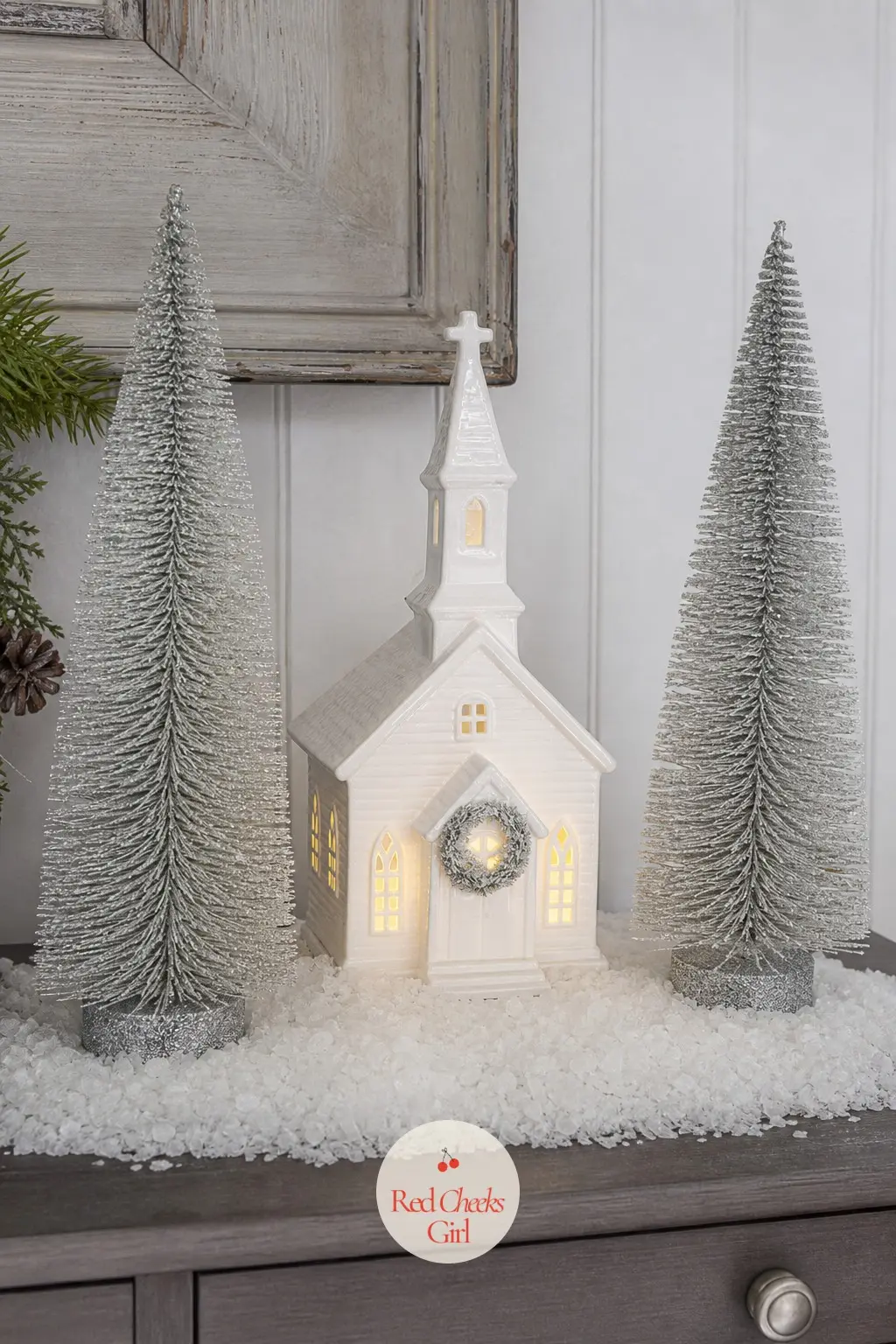 A Single Lit Chapel on Rock Salt Snow With Silver Bottle Brush Trees — Skip the full village grid and give one building the whole shelf. Christmas shelf decor
