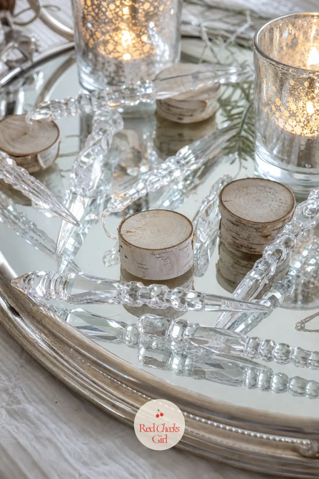 A Mirror Tray Scattered With Crystal Icicle Ornaments and Birch Rounds — A mirrored tray doubles every bit of light that lands on it, which makes this one of