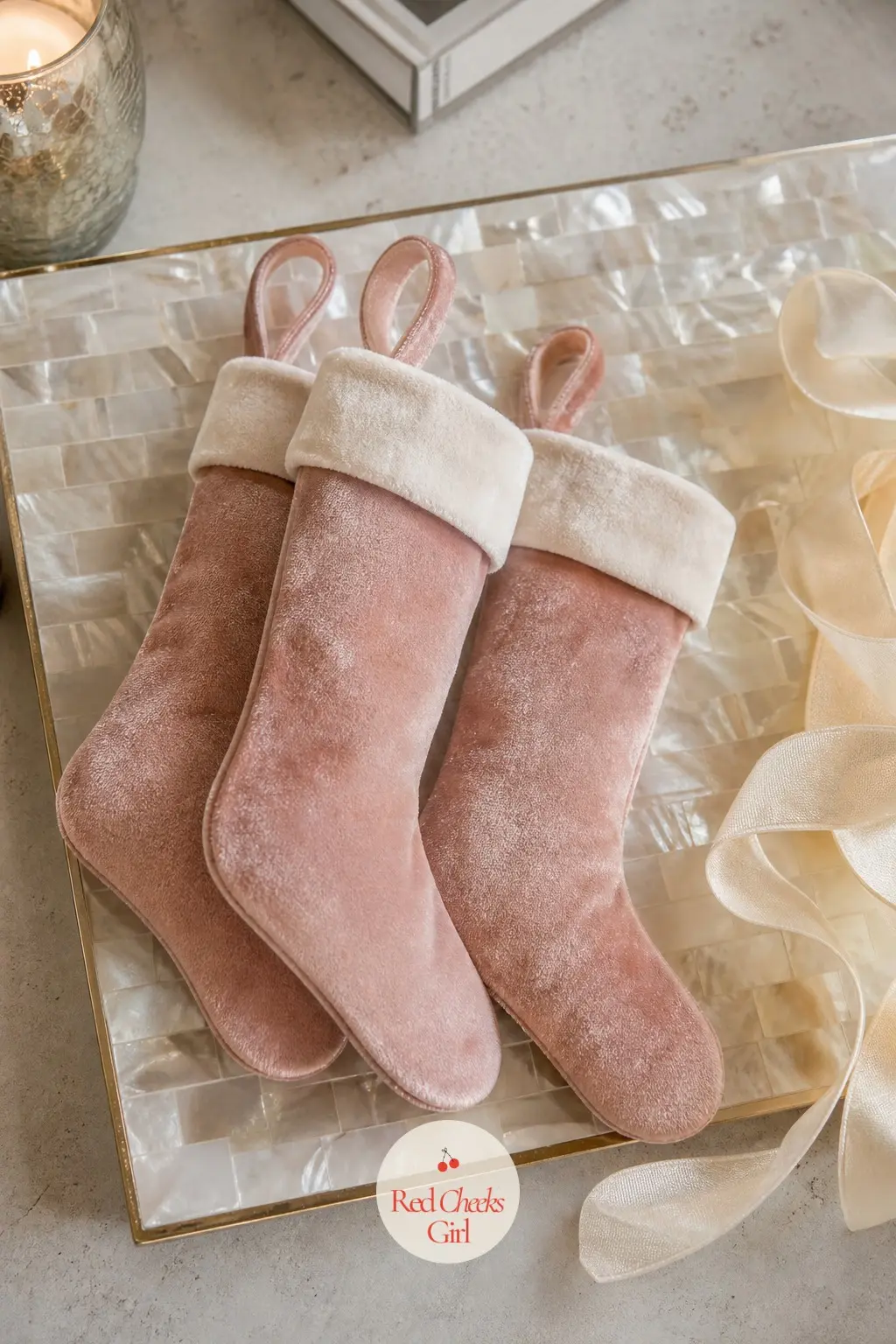 A Mother of Pearl Tray With a Trio of Blush Velvet Stockings in Miniature — Three miniature stockings in blush velvet lean against each other on a mother of