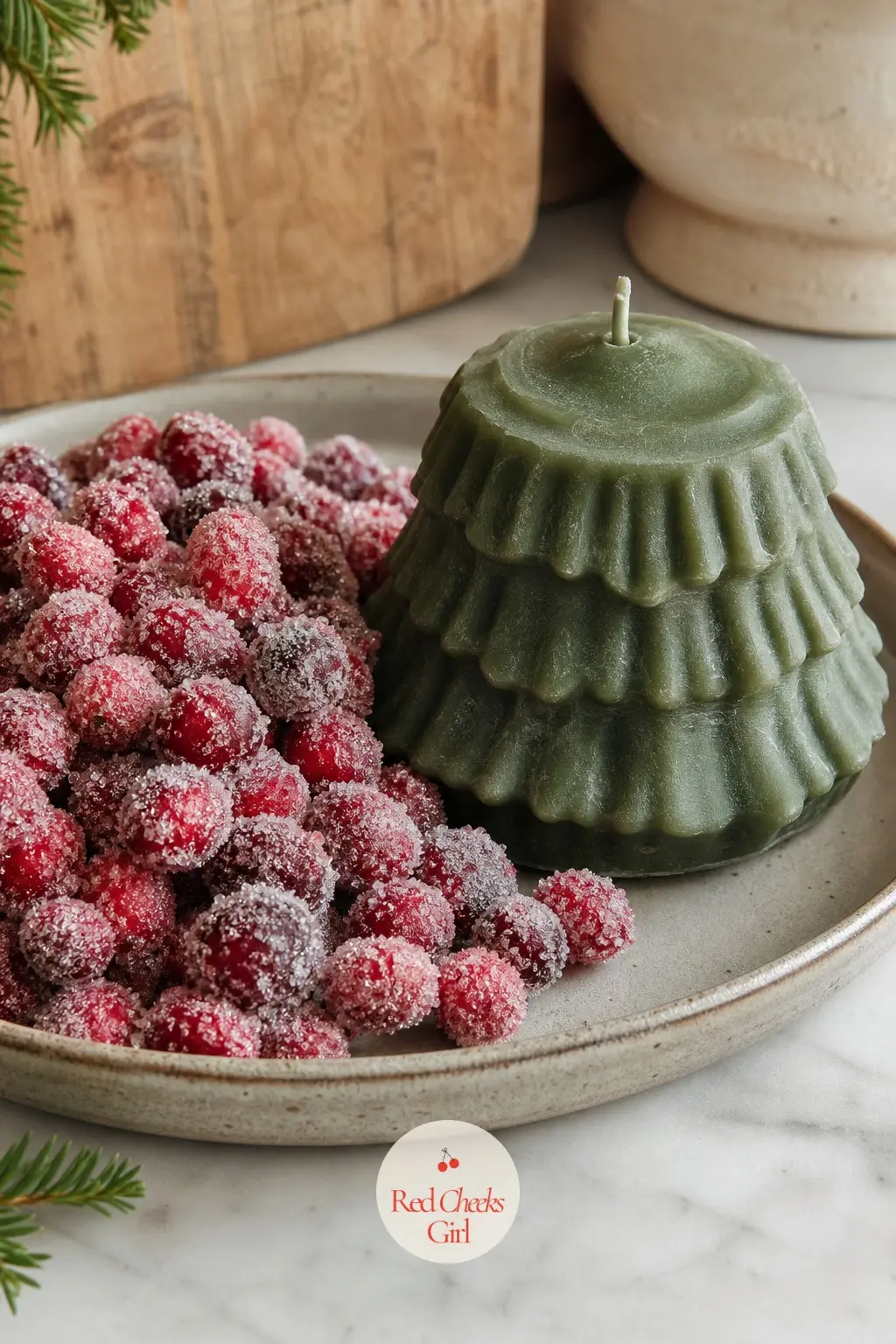 A Stoneware Tray of Sugared Cranberries Piled Beside a Squat Pine Candle — A generous pile of sugared cranberries in deep red sits on one side of a stoneware