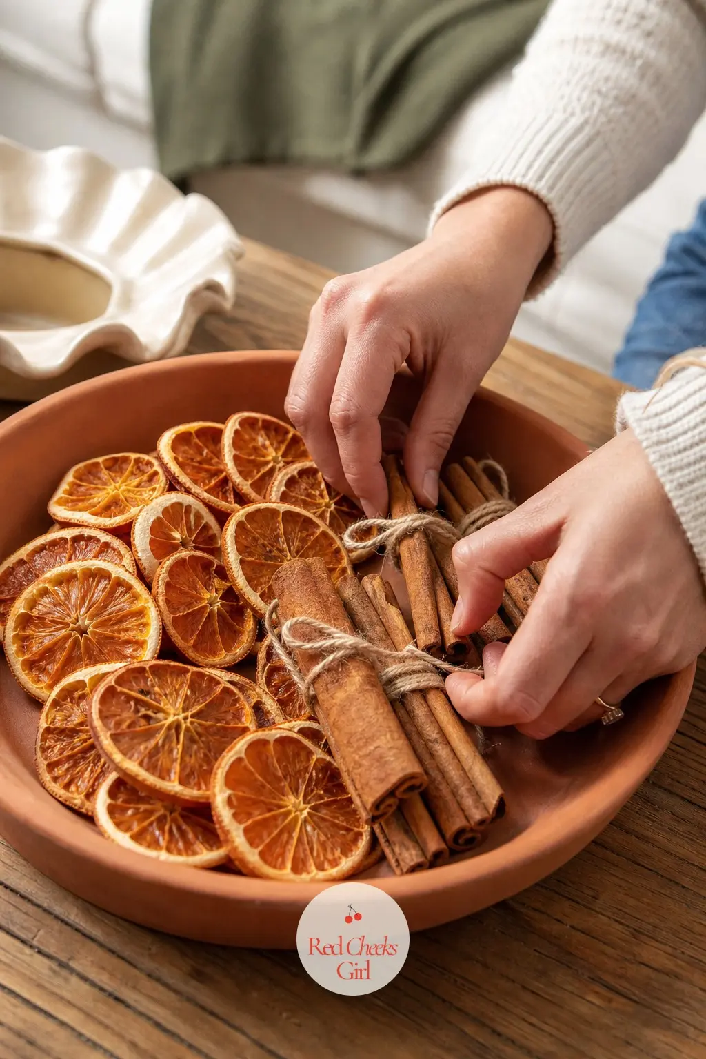 A Terracotta Tray of Dried Orange Wheels and Bundled Cinnamon Quills — Dried orange wheels in burnt orange fan out around small bundles of cinnamon quills tied