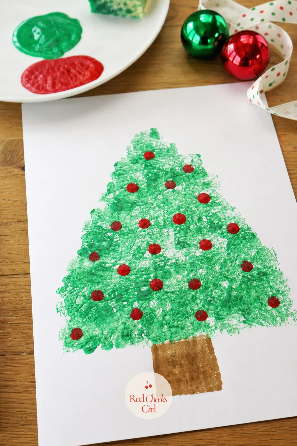 Sponge-Painted Dot Tree — A sea sponge dipped in kelly green paint and dabbed down a drawn triangle outline builds a textured tree in under five minutes, no