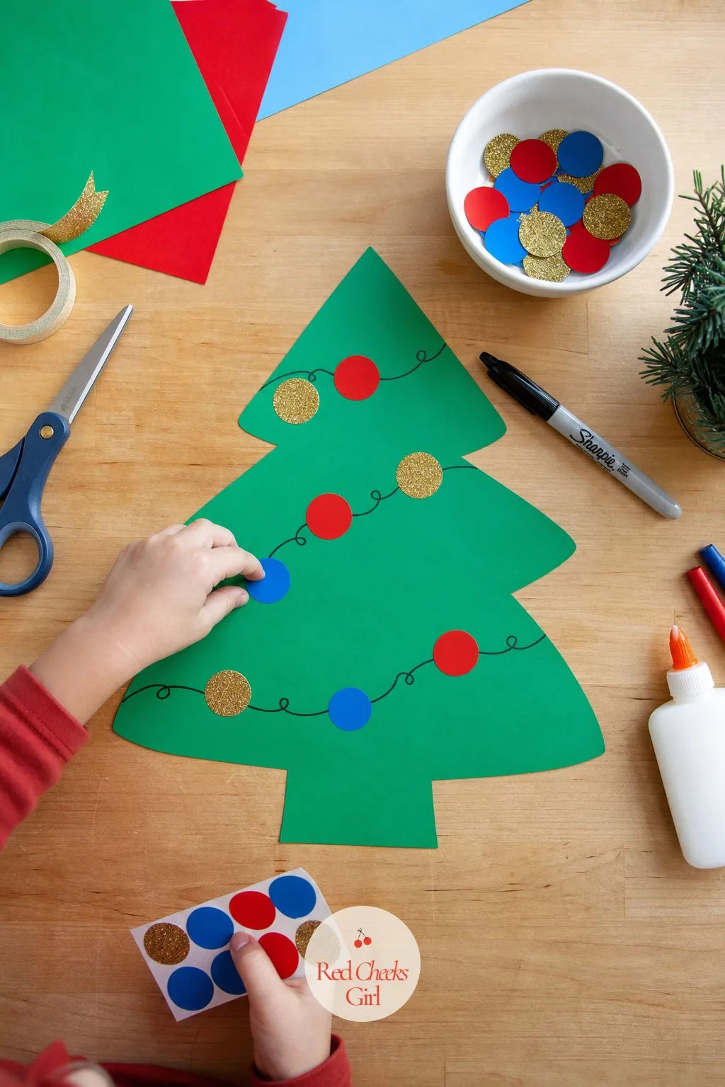 Sticker Garland Tree — A tree shape cut from green construction paper, a marker line drawn across it for a garland, and a sheet of Christmas stickers in red