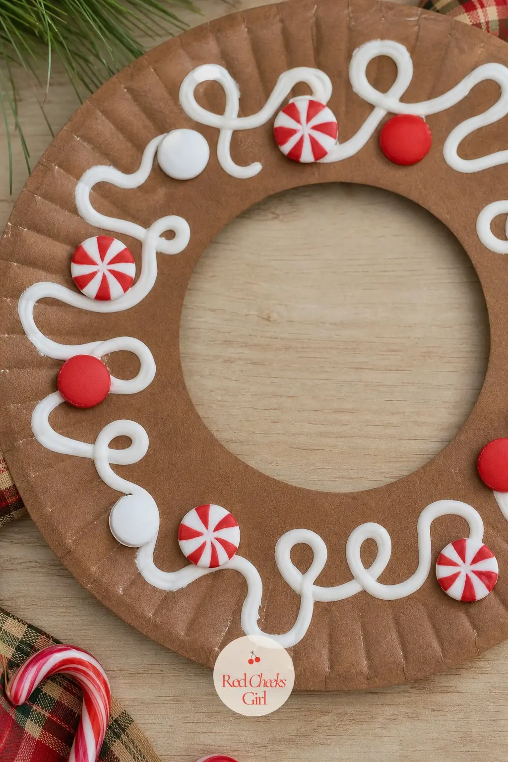 Gingerbread Paper Plate Wreath — A brown paper plate ring gets squeezed lines of white puffy paint in swirls and dots, meant to look like icing. Christmas