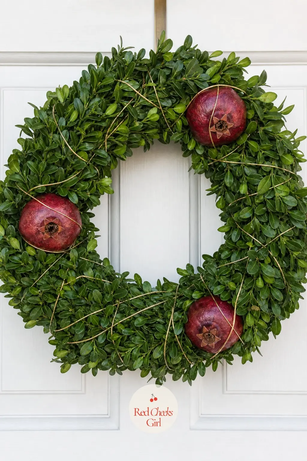 Boxwood and Pomegranate Wreath — Dense boxwood green studded with dried pomegranates in deep burgundy, wrapped through with thin gold wire. Christmas wreaths