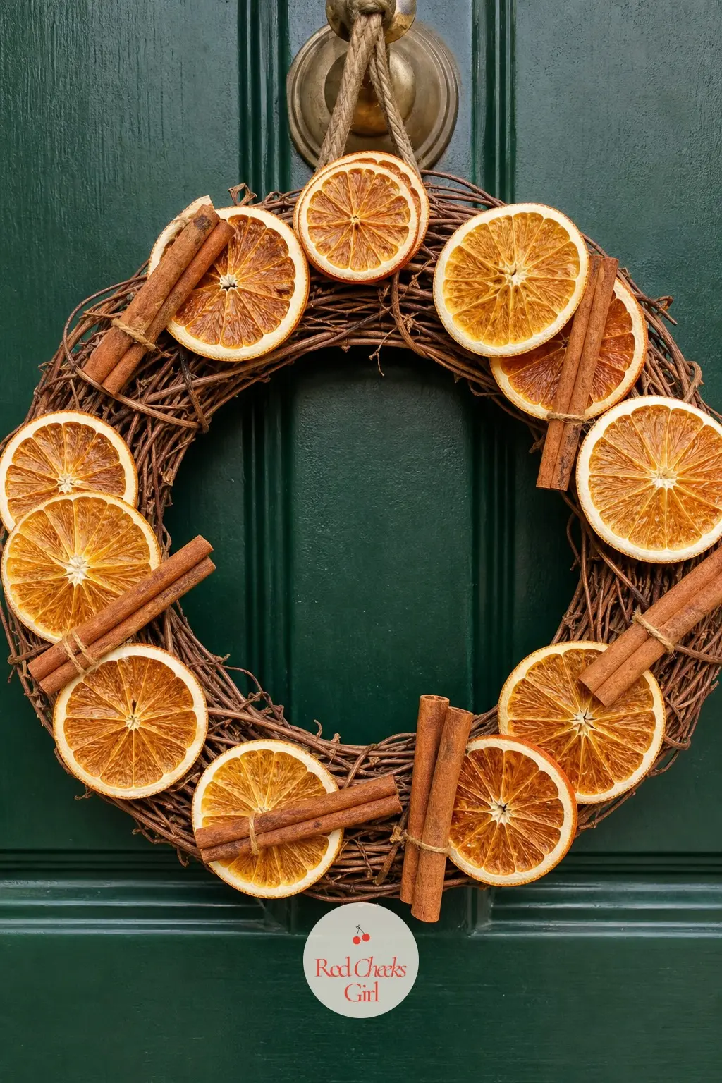 Dried Orange Slice and Cinnamon Wreath — Burnt orange dried citrus slices strung with cinnamon sticks and cream linen ribbon, built on a plain grapevine base.